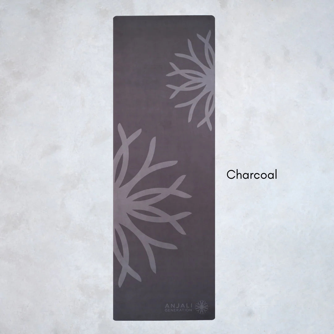 Charcoal-colored Anjali Generation eco suede yoga mat with floral patterns on a light gray background