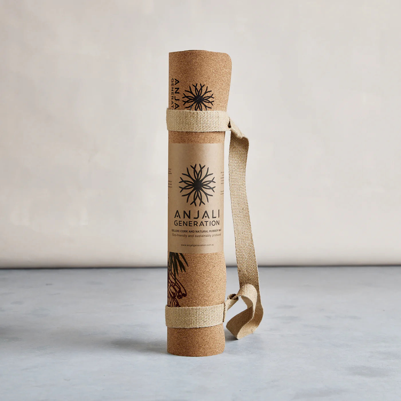 Anjali Generation cork yoga mat with carrying strap on a light background