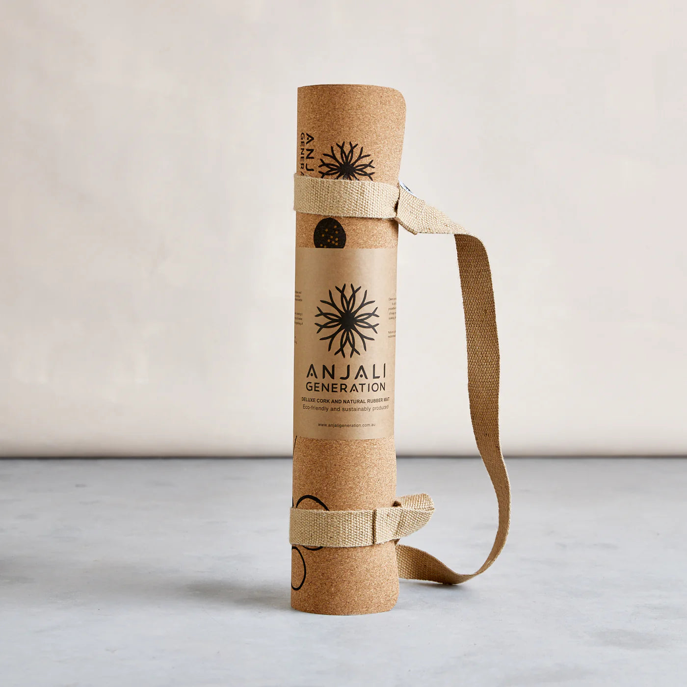 Anjali Generation cork yoga mat with carrying strap on a light background