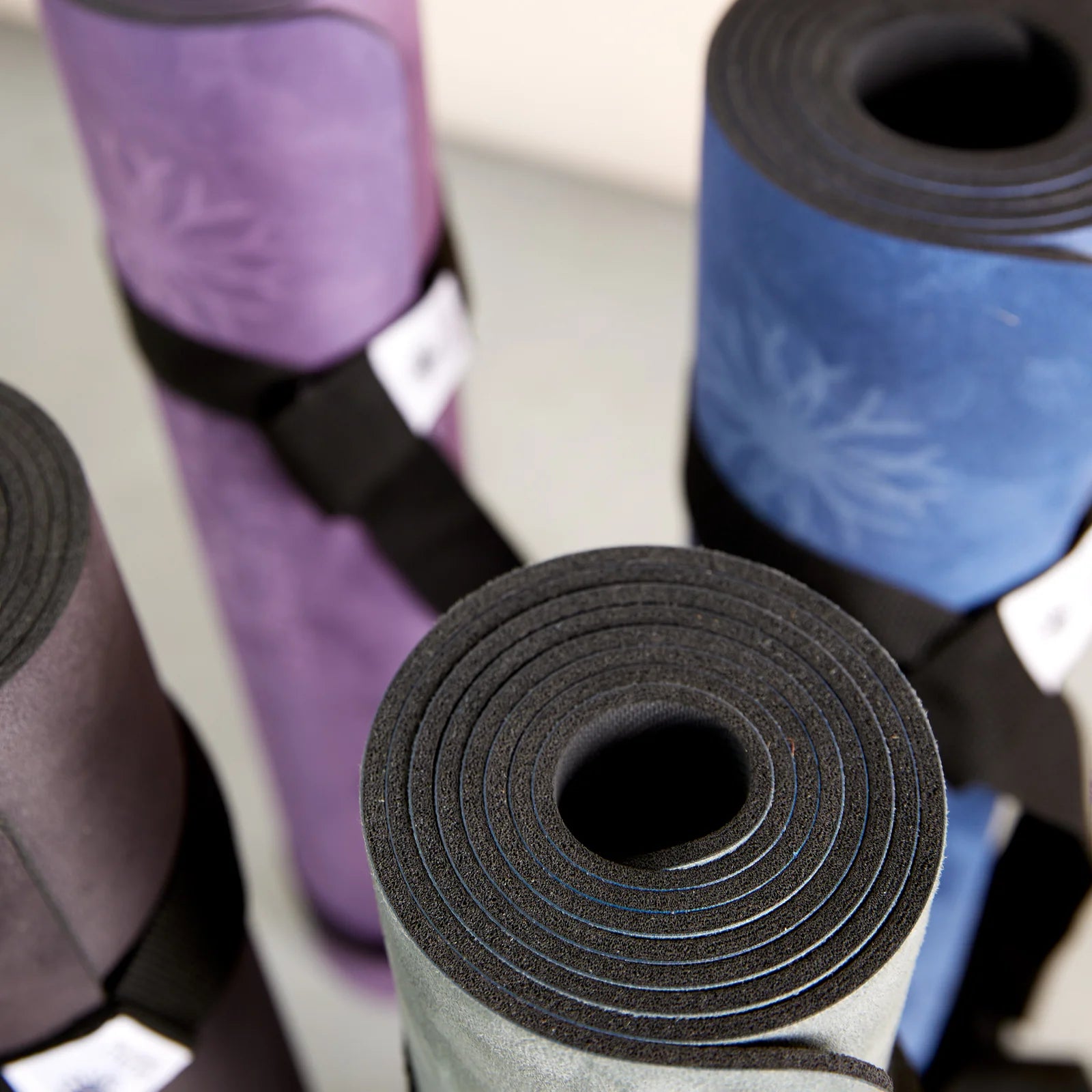 Rolls of Anjali Generation eco suede yoga mats in various colors on a light background