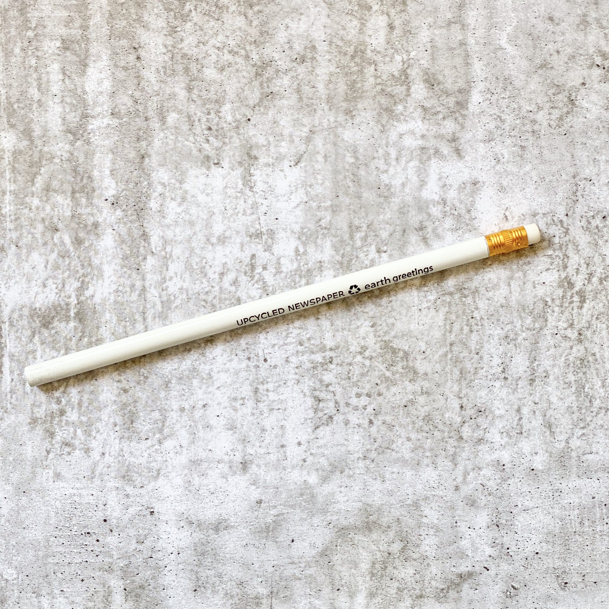 Earth Greetings recycled newspaper pencil on a textured gray surface