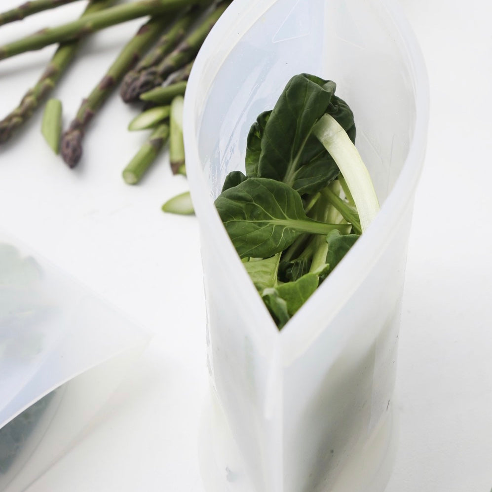 Ever Eco White reusable silicone food pouches with green leafy vegetables and asparagus on a white background