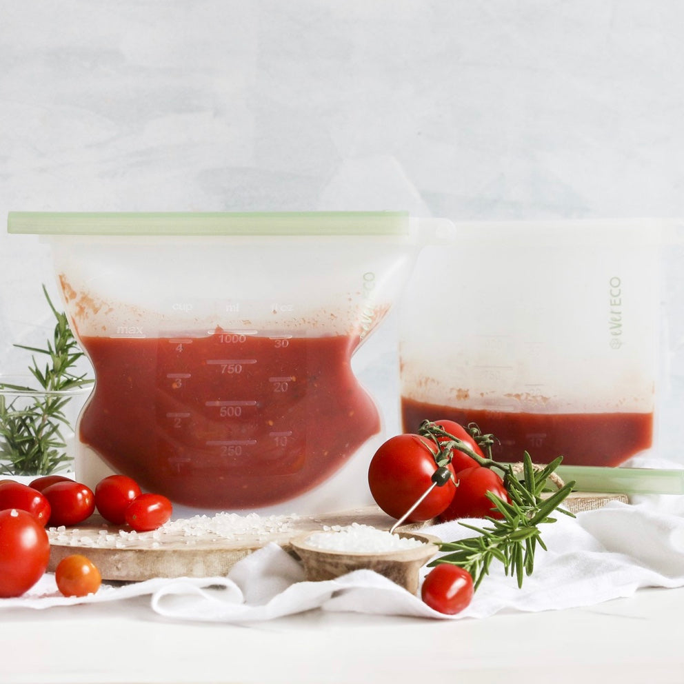 Tomato-based product in an Ever Eco reusable silicone food pouch with fresh tomatoes and rosemary on a white background