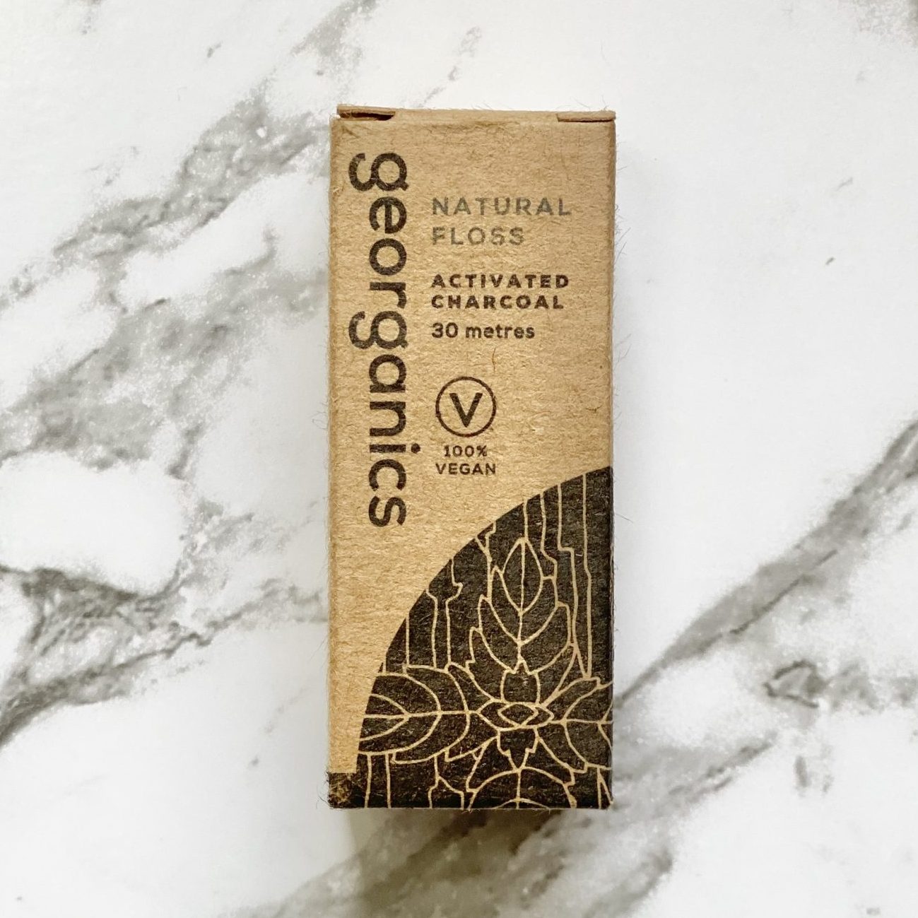 Georganics natural activated charcoal floss box on a marble background