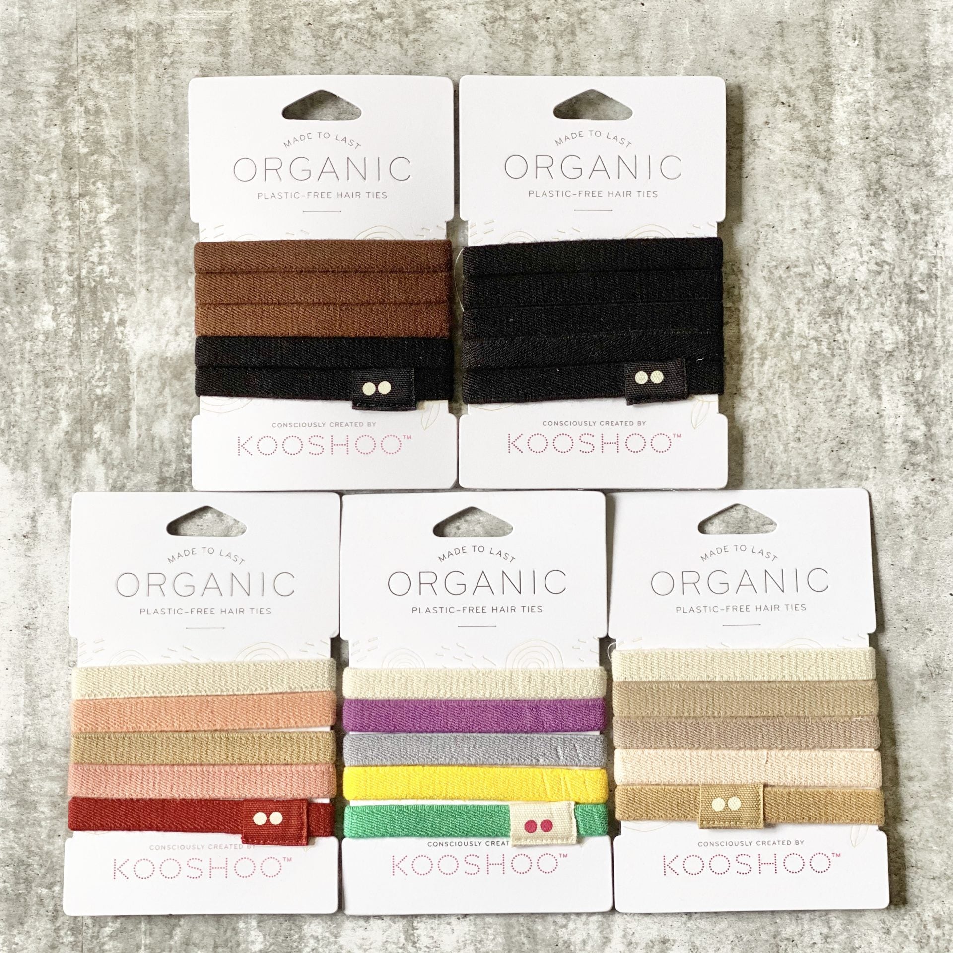 Kooshoo organic hair ties in various colors on gray concrete background
