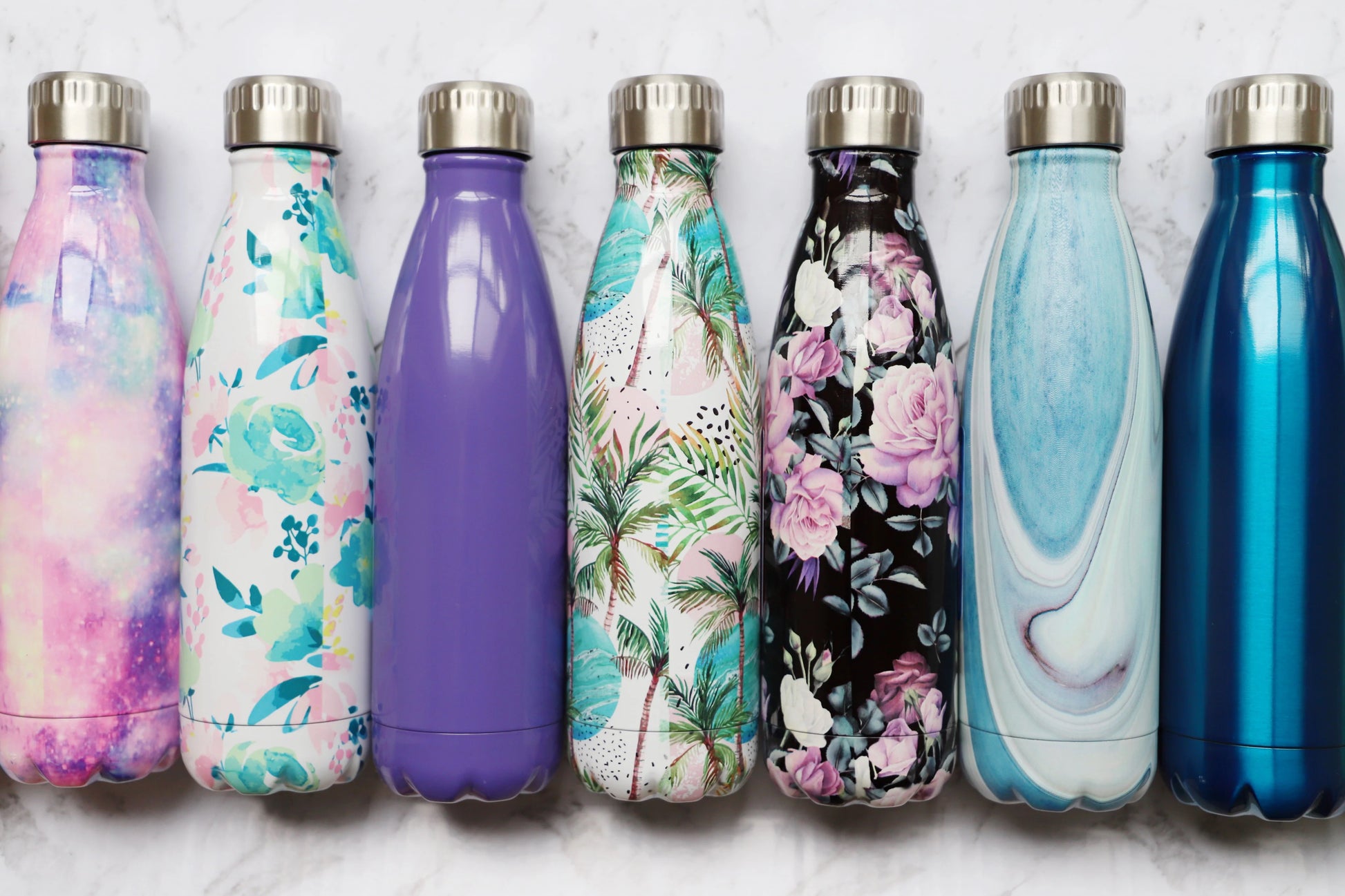 Set of colorful Oasis 500ml stainless steel water bottles with floral and abstract designs on a light background
