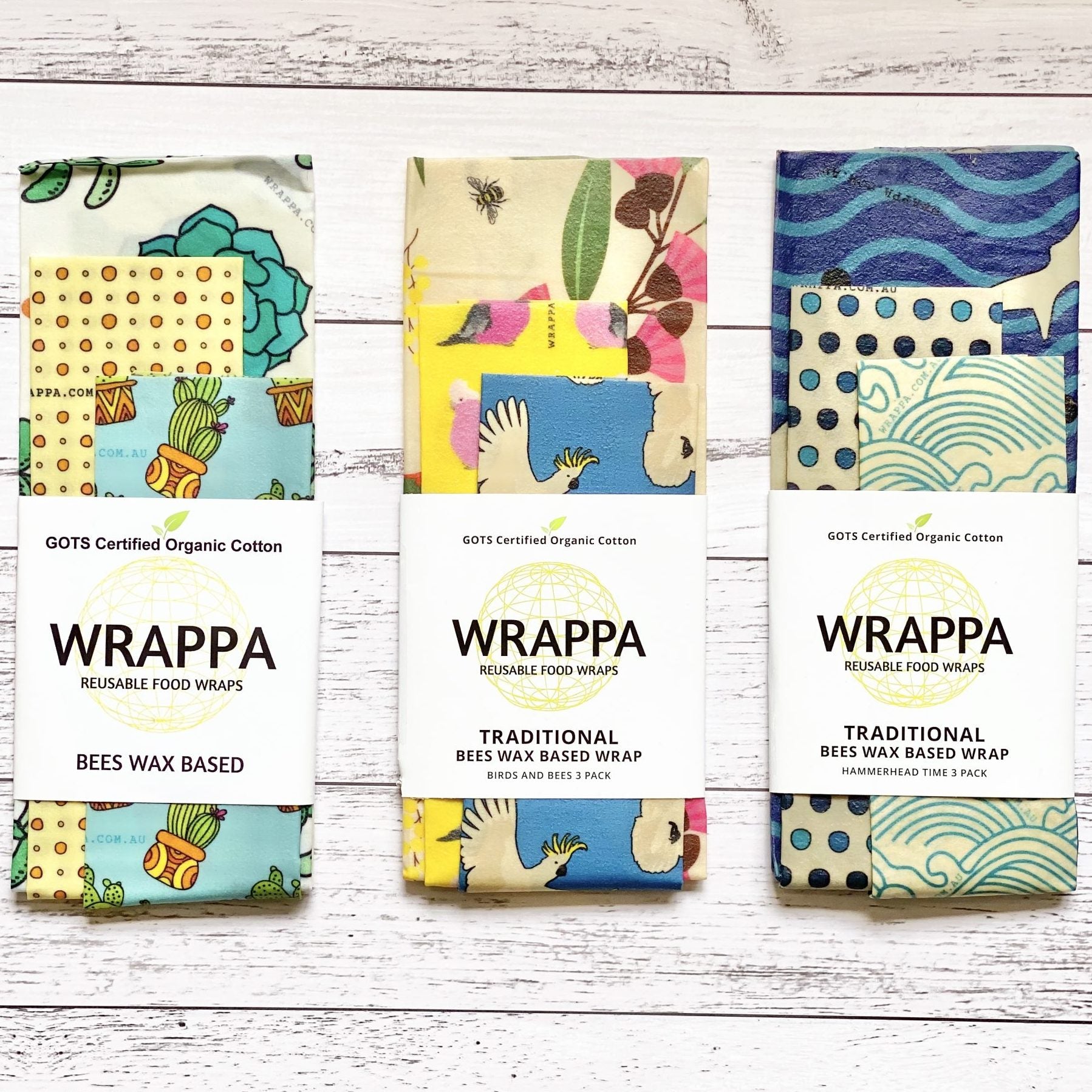 Three packages of WRAPPA reusable beeswax food wraps with colorful designs on a wooden surface.