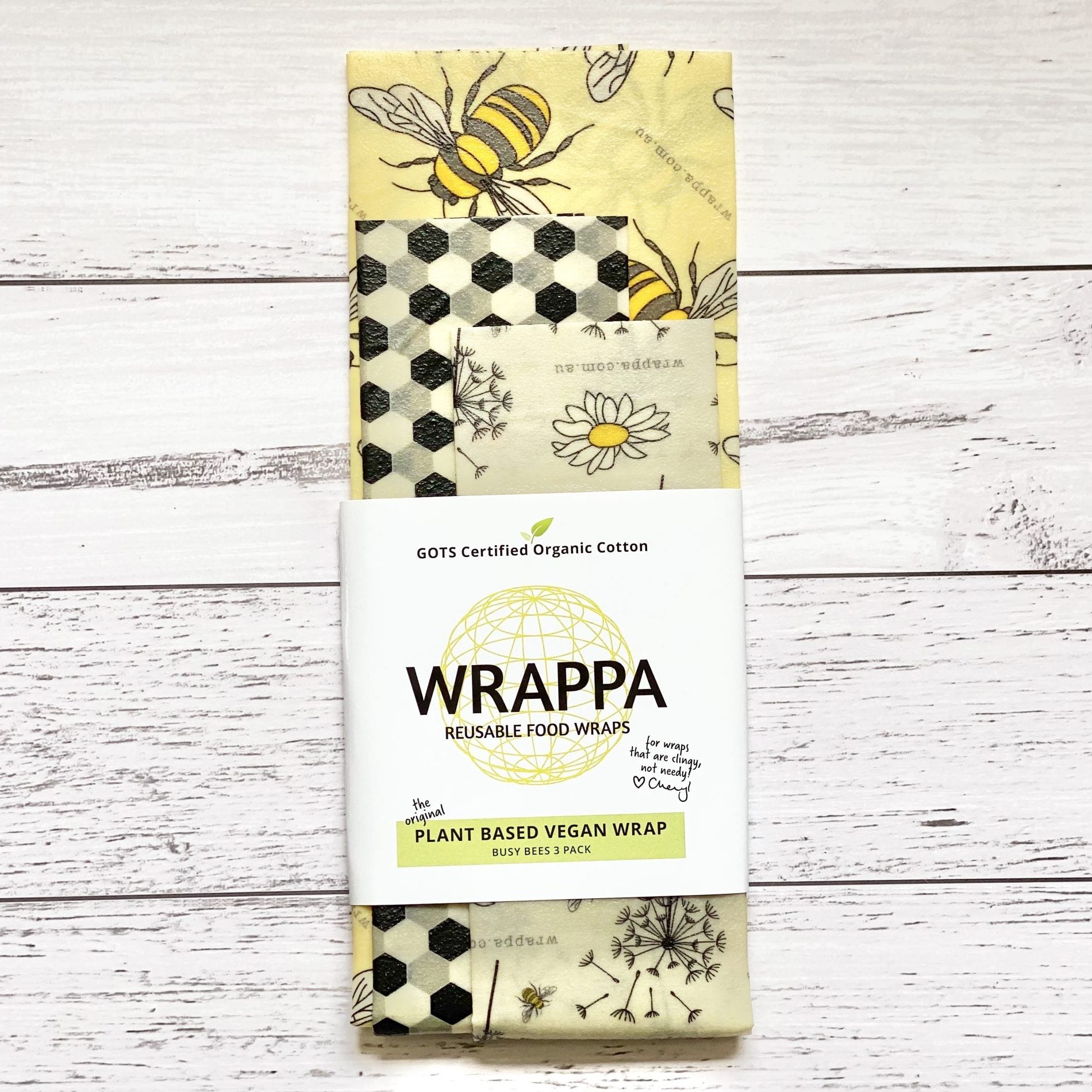 Pack of Wrappa plant-based vegan reusable food wraps with bee and honeycomb design on a wooden surface