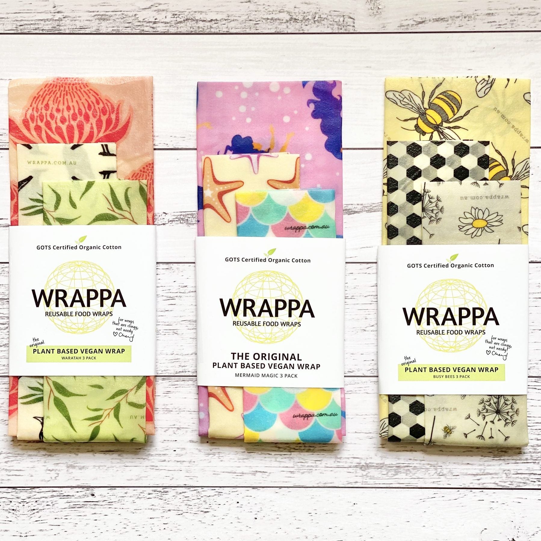 Three packages of WRAPPA plant-based vegan reusable food wraps with colorful designs on a wooden surface.