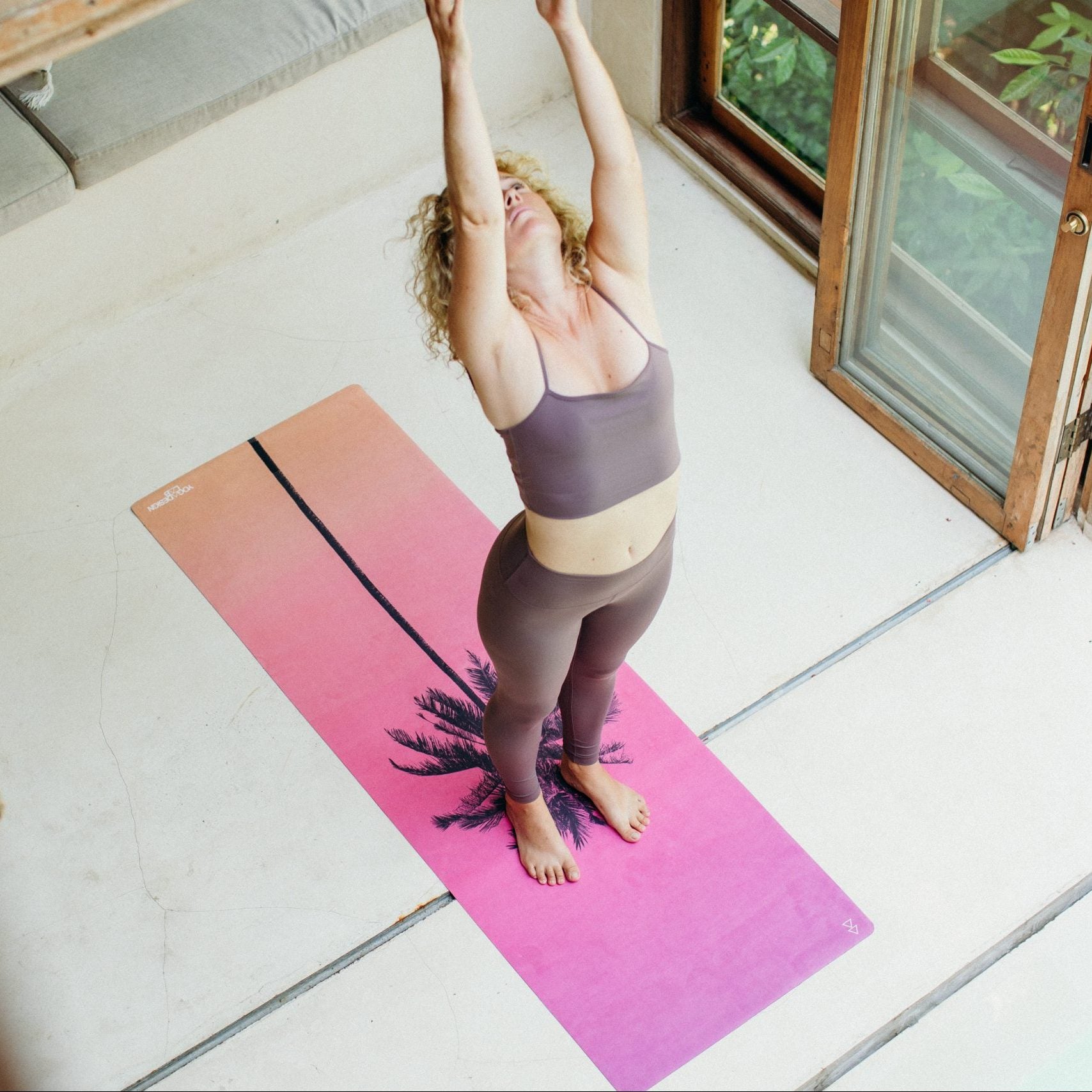 Woman practicing yoga on a pink and purple Yoga Design Lab combo mat indoors.