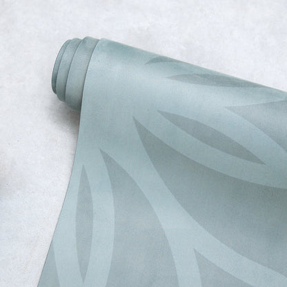 Rolled Anjali Generation eco suede light green yoga mat with leaf pattern on a textured surface