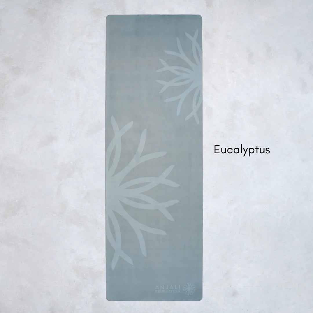 Green Anjali Generation eco suede yoga mat with eucalyptus design on a light gray background