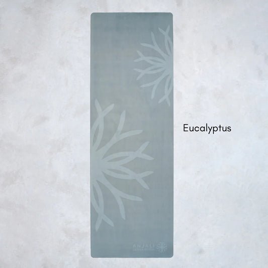 Green Anjali Generation eco suede yoga mat with eucalyptus design on a light gray background