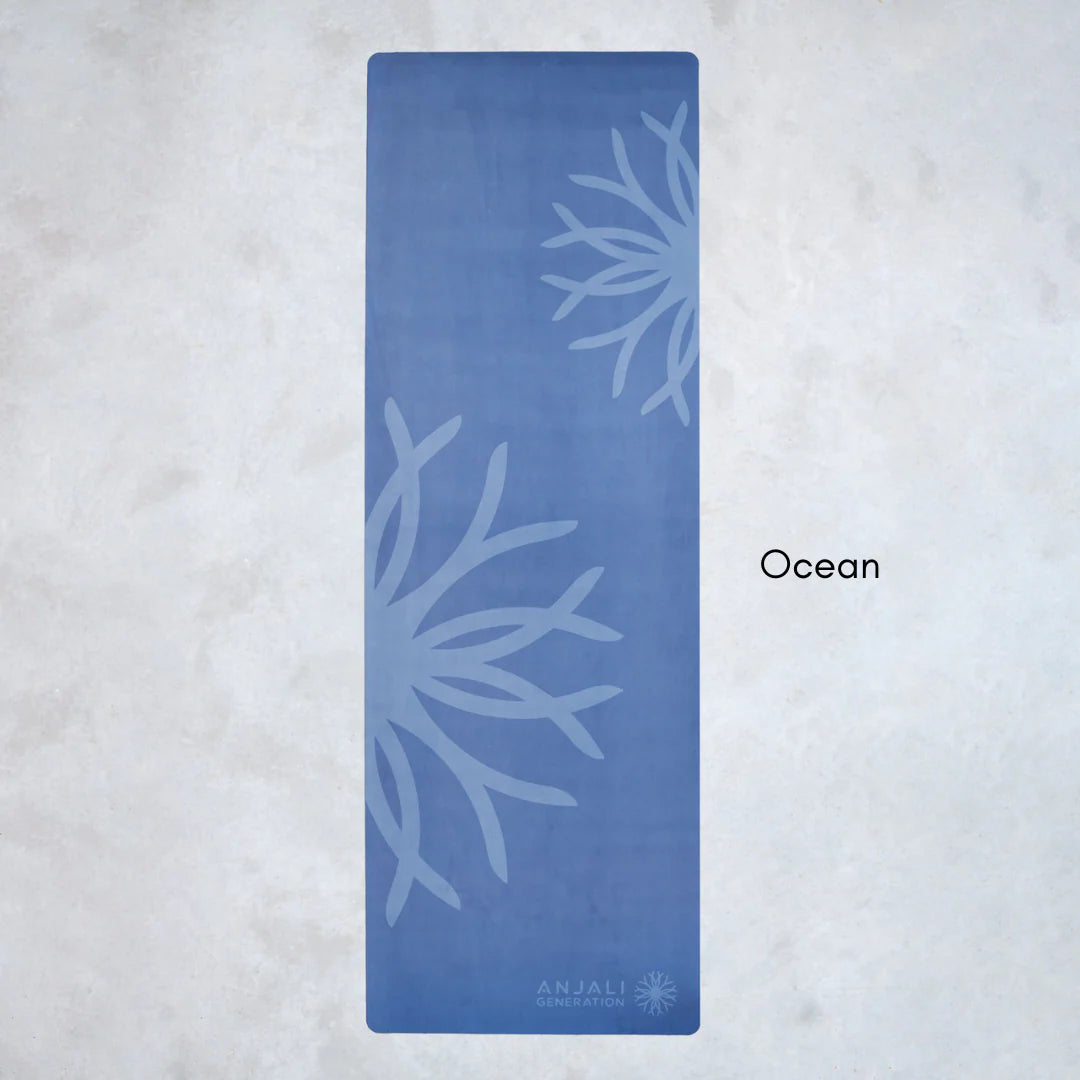Blue Anjali Generation eco suede yoga mat with coral design on a light gray background