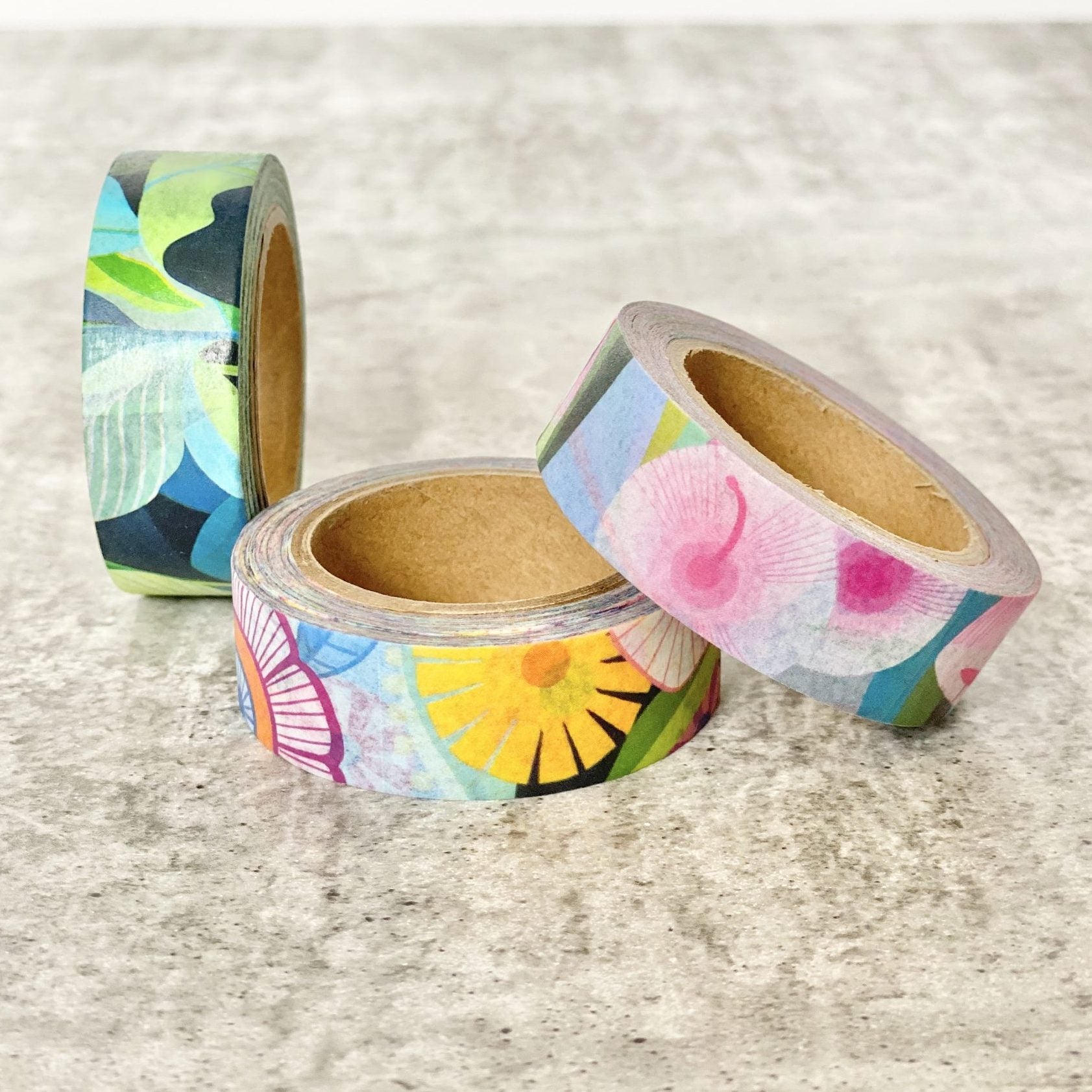 Three rolls of colorful Earth Greetings brand washi tape on a textured surface