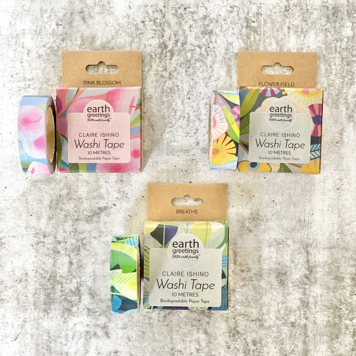 Three rolls of Earth Greetings Claire Ishing Washi Tape with colorful designs on a textured surface