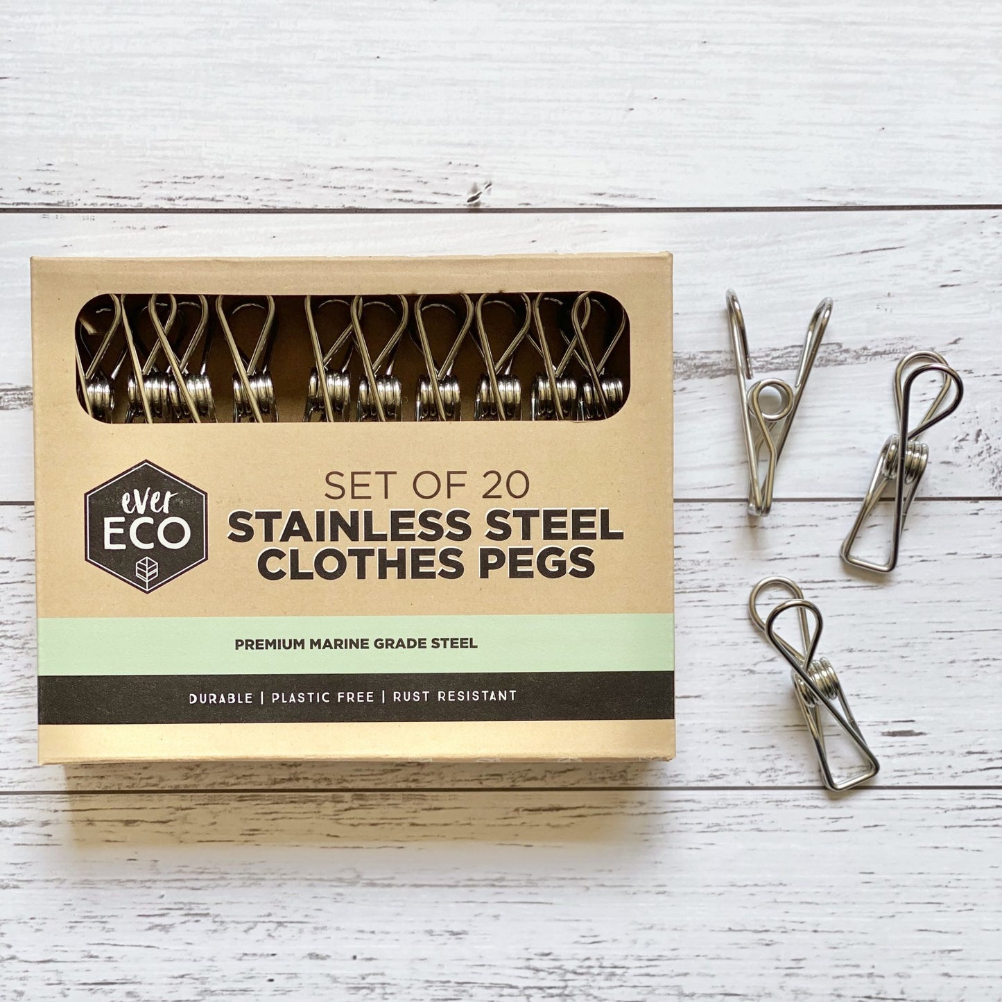 Set of 20 Ever Eco stainless steel clothes pegs with recyclable packaging on a wooden surface
