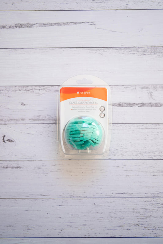 Full Circle turquoise cellulose glass cleaner ball with packaging on a light wooden surface