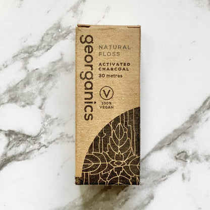 Georganics natural activated charcoal floss box on a marble background