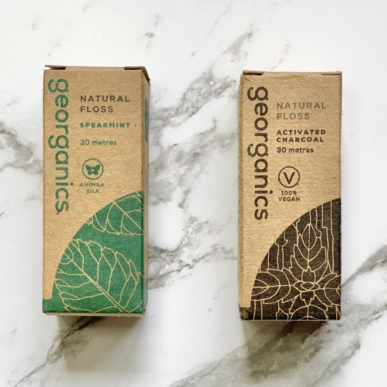 Two boxes of Georganics dental floss on a marble surface
