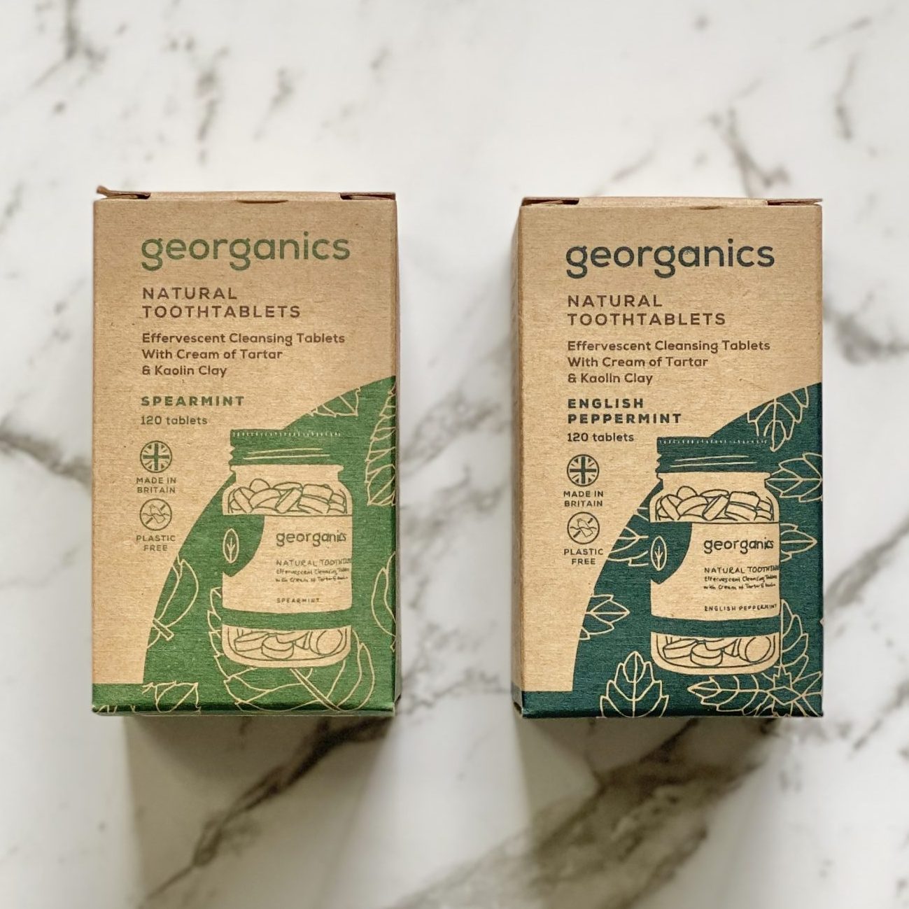 Two boxes of Georganics natural tooth tablets in spearmint and English peppermint on a marble surface