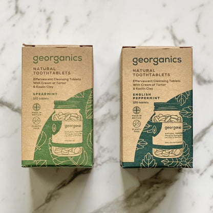 Two boxes of Georganics natural tooth tablets in spearmint and English peppermint on a marble surface
