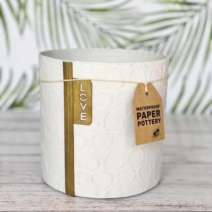 EcoMax paper pot in white with heart pattern with decorative tags on a wooden surface