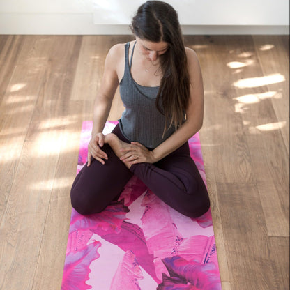 Woman stretching on a pink Yoga Design Lab combo  mat in a well-lit room